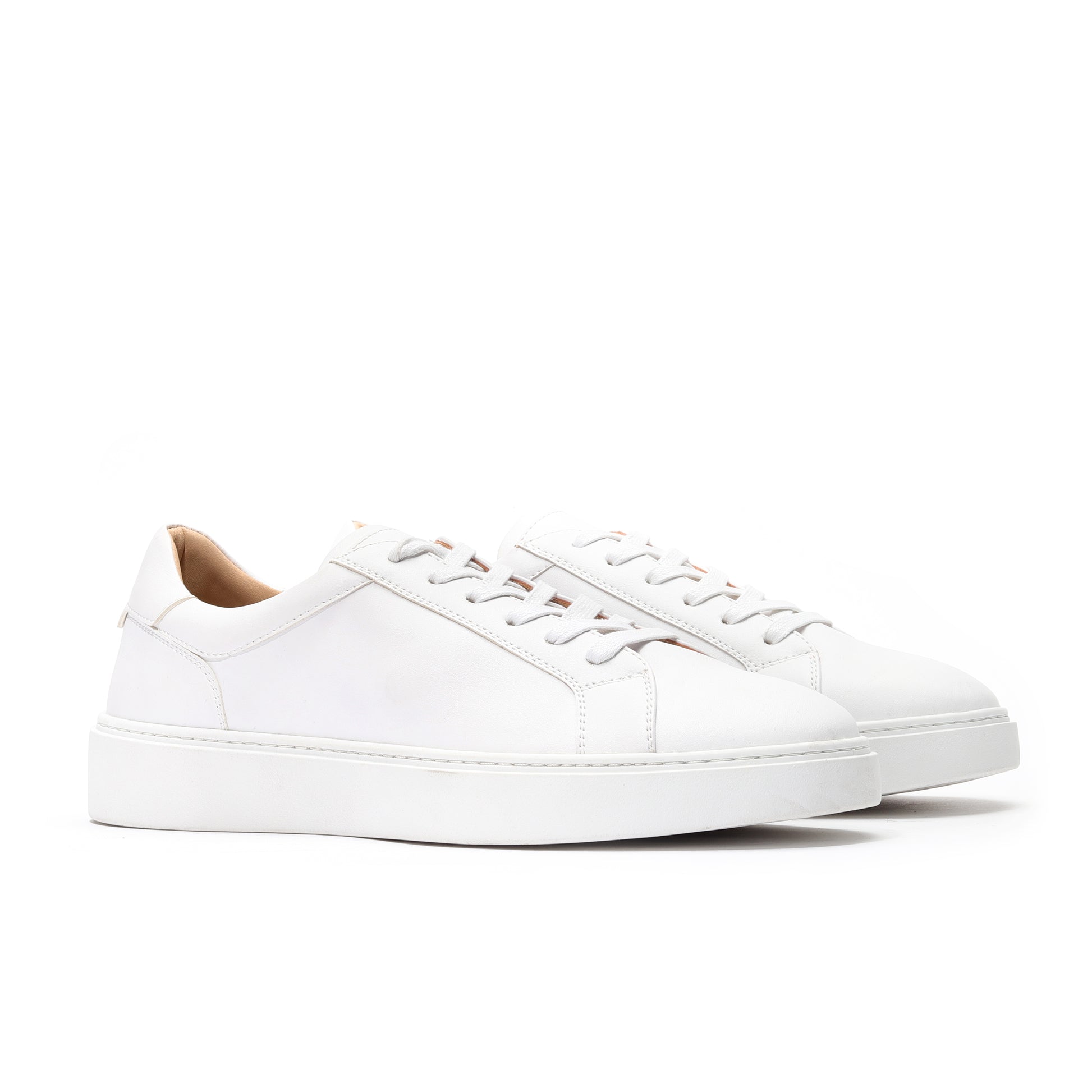 Angled view of white leather sneakers for men with low-top design and cushioned comfort.